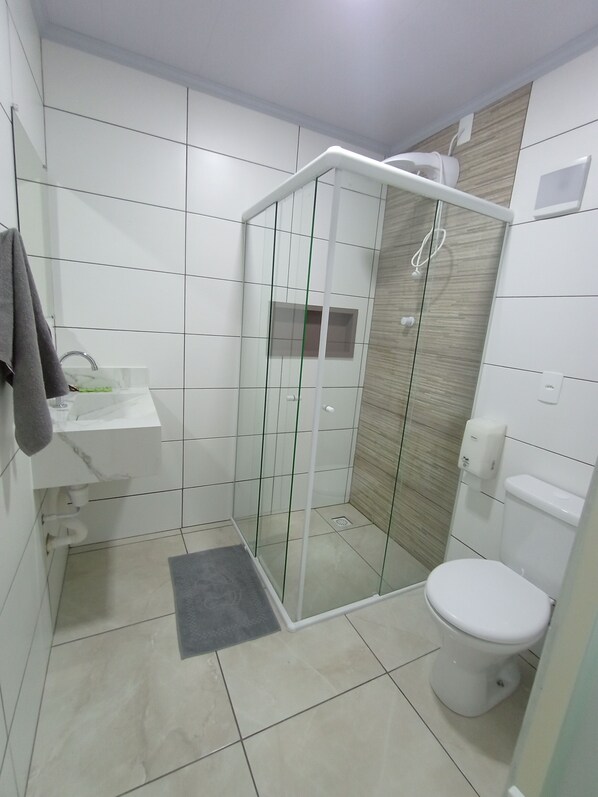 A modern bathroom with a glass-enclosed shower, a white sink, and a toilet.