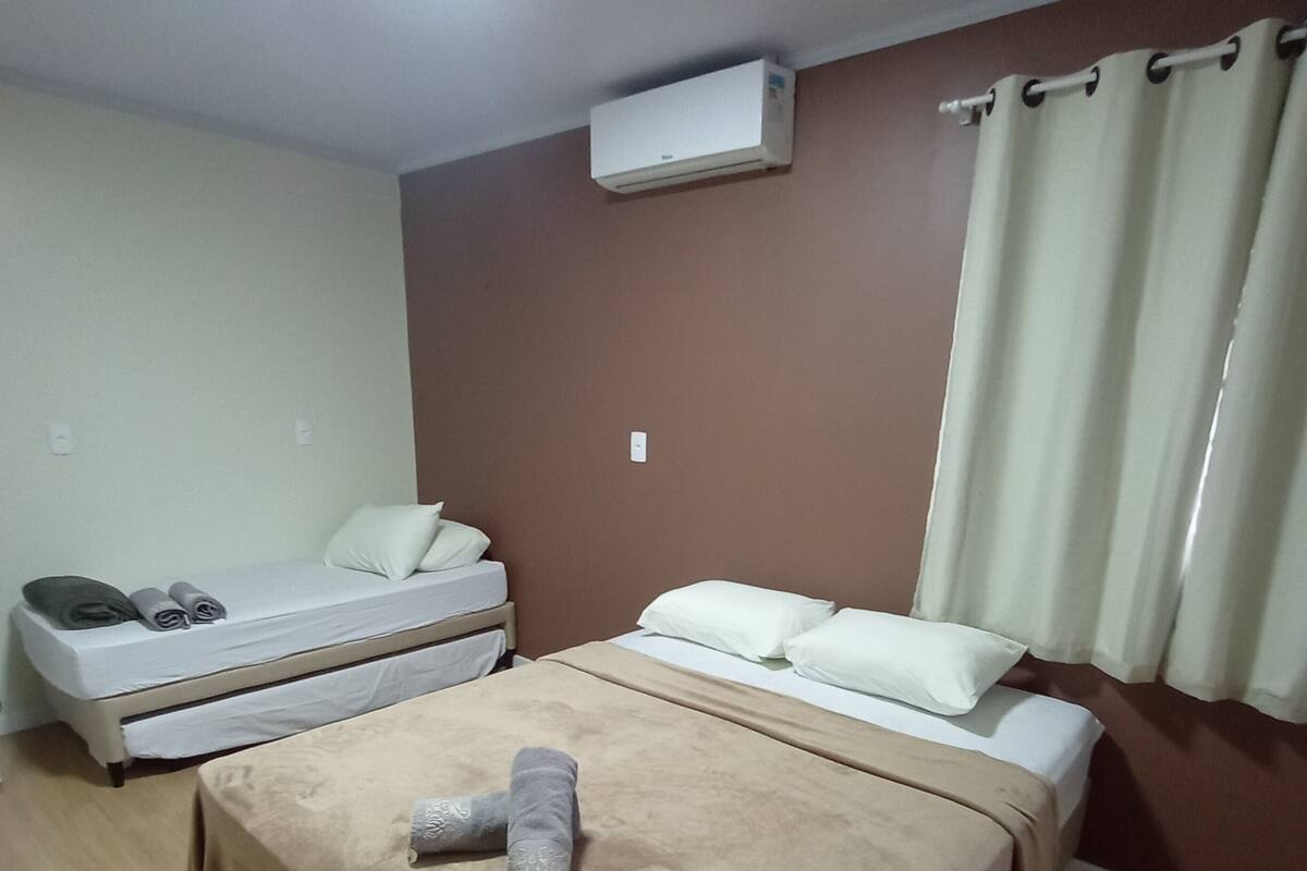 Egy szállodai szoba két ággyal, mennyezeti ventilátorral, légkondicionálóval és függönnyel ellátott ablakkal.