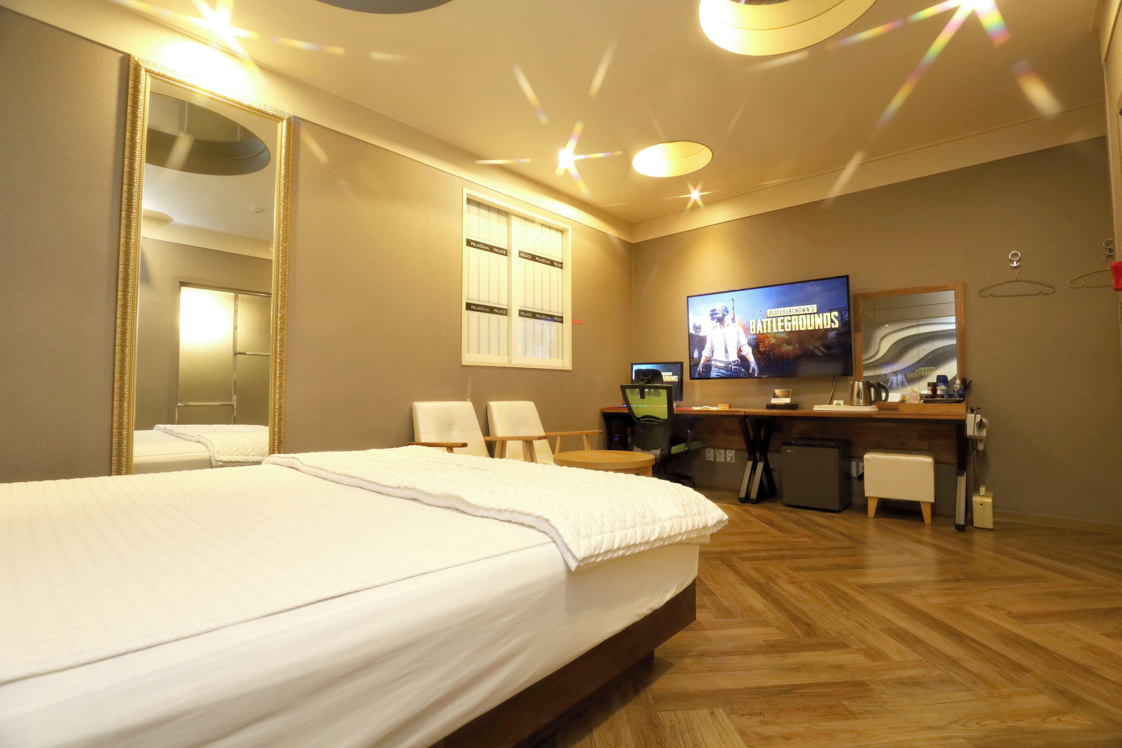 A hotel room with a large bed, a desk with a computer, a television, and a mirror.