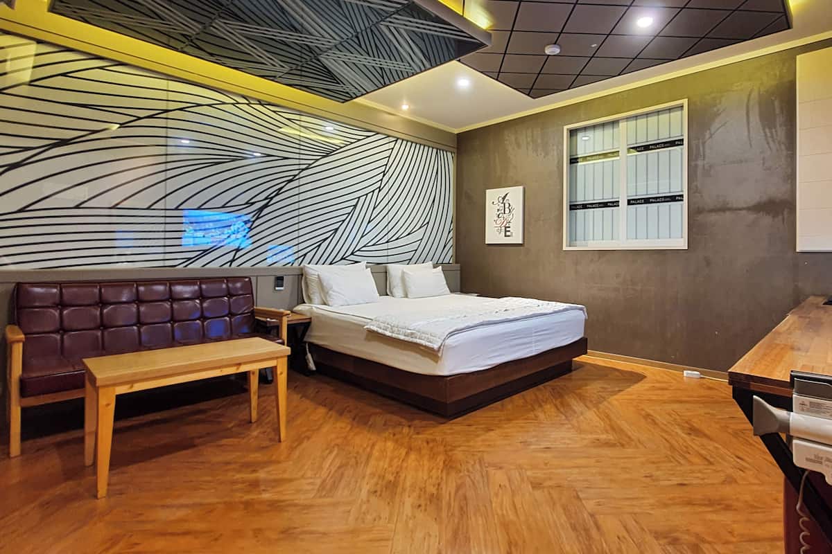 A modern bedroom with a large bed, a wooden bench, and a unique wall design.
