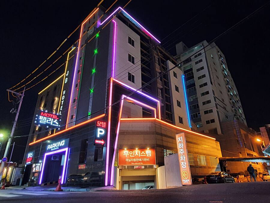 A building with neon signage, including a motel and parking area.