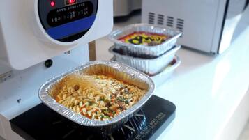 Una cocina con una placa de inducción y dos sartenes de aluminio encima.
