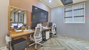 A hotel room with a large desk, two office chairs, a flat-screen TV, a mirror, and a minibar. - Ulsan Palace (Ulsan)