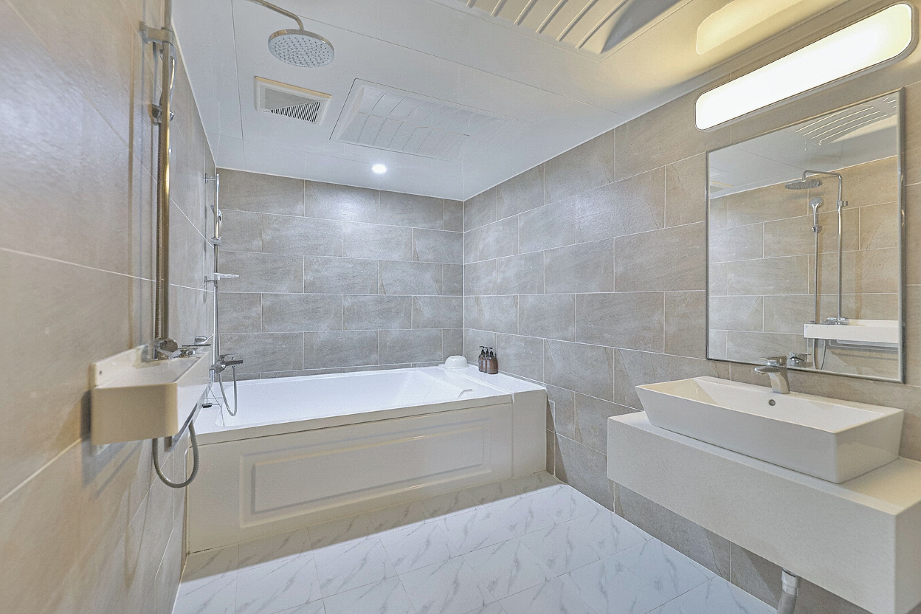 A modern bathroom with a bathtub, a sink, and a large mirror.
