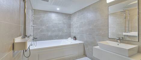 A modern bathroom with a bathtub, a sink, and a large mirror.
