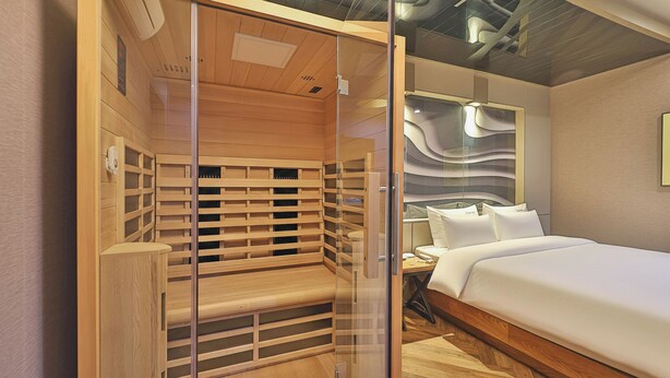 A modern hotel room with a wooden bench, a bed, and a glass partition. - Ulsan Palace (Ulsan)