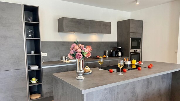 Una cocina moderna con una isla central, estanterías empotradas y un microondas.