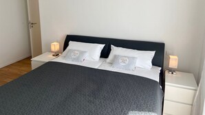 Una cama bien hecha con cabecera oscura, ropa de cama blanca y dos lámparas de noche.