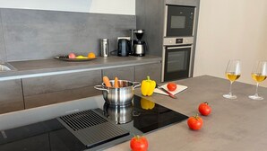 Una cocina moderna con placa de inducción, hervidor, cafetera y microondas.