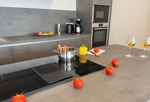 A modern kitchen with an induction cooktop, a kettle, a coffee maker, and a microwave. - 2915 Wohnung 5 - 2915 - Strandwiese 1 - Wohnung 5 (Dahme)