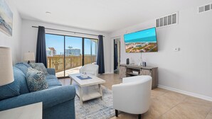 A modern living room with a sofa, armchair, coffee table, and a TV mounted on the wall. - La Mirage Condo 106 Beachfront Resort Condominiums with Private Boardwalk (Port Aransas)