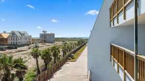 Un edificio frente al mar con un balcón que da a una playa de arena y al océano.