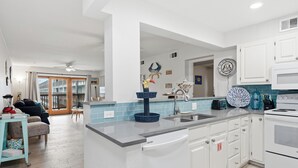 A modern kitchen with white cabinets, a built-in dishwasher, and a large island with a sink. - La Mirage Condo 218 Beachfront Resort Condominiums with Private Boardwalk (Port Aransas)