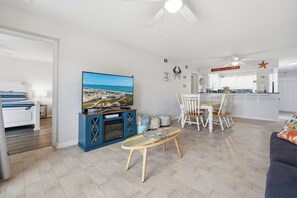 A modern living room with a TV, a dining area, and a kitchen.