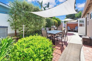 Enjoy al fresco dining in a serene outdoor setting with a table, chairs, barbecue grill, and comfortable seating area.
