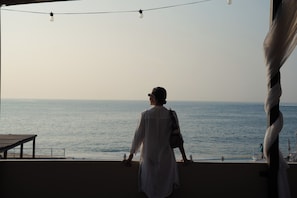 A person standing on a balcony overlooking the sea, with string lights above and a view of the ocean. - 9 Bahias Condos  (Santa María Huatulco)