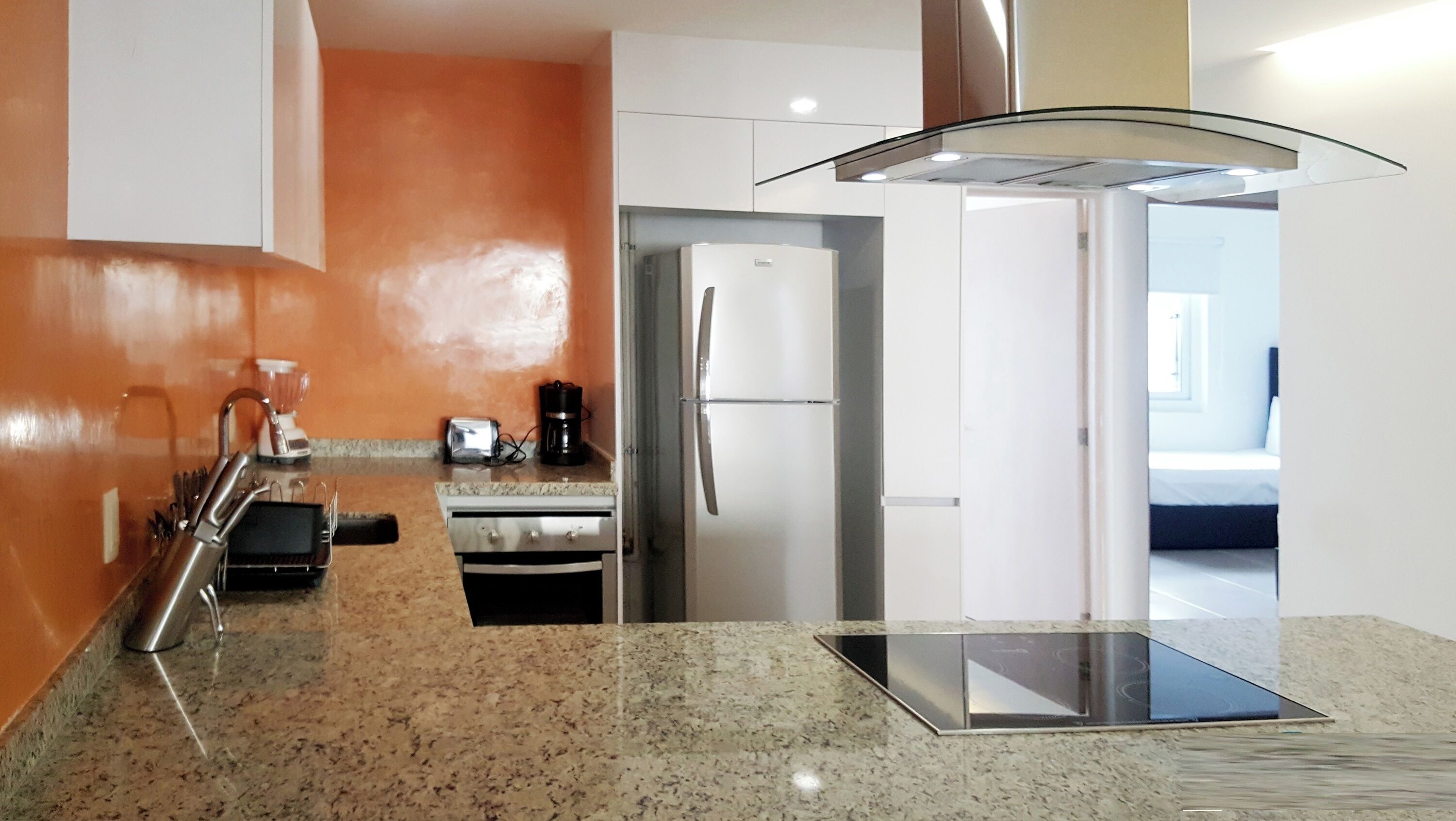 A modern kitchen with granite countertops, stainless steel appliances, and a glass ceiling light fixture.