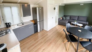 A compact kitchen with modern appliances, a dining area with a round table and chairs, and a cozy seating area with a sofa. - Gorgeous home in Tzummarum with WiFi (Tzummarum)