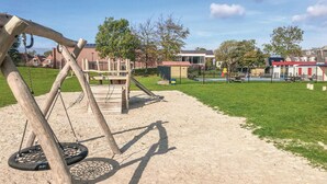A playground with swings and tire swings, surrounded by a grassy area and houses in the background. - Gorgeous home in Tzummarum with WiFi (Tzummarum)