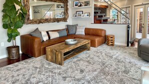 Ein modernes Wohnzimmer mit einer braunen Ledersofa, einem Holztisch und einem großen Spiegel.