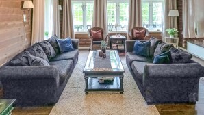 Een woonkamer met twee tegenover elkaar geplaatste banken, een salontafel in het midden, en een uitzicht op de buitenlucht door grote ramen.