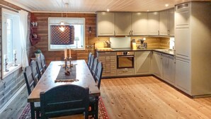 Een eetgedeelte met een houten tafel en stoelen, een kroonluchter en een raam met gordijnen.