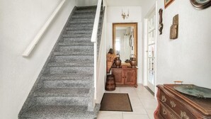 Eine Treppe führt zu einem Raum mit einem Holzschrank und einem Spiegel.