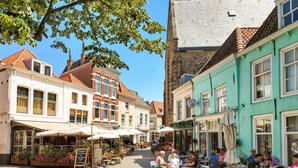Eine Kopfsteinpflasterstraße gesäumt von traditionellen europäischen Gebäuden, mit Straßencafés und blauem Himmel.