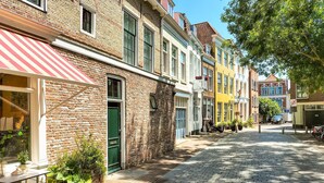 Eine Kopfsteinpflasterstraße gesäumt von farbenfrohen Gebäuden, einer grünen Tür und Außenplätzen.