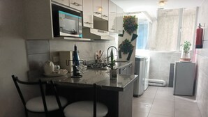 A modern kitchen with a central island, bar stools, a microwave, and a gas stove. - Loft Shandde Park (Quito)
