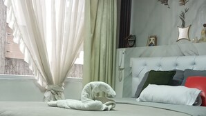 A bedroom with a large bed, a headboard with decorative elements, and a window with sheer curtains. - Loft Shandde Park (Quito)