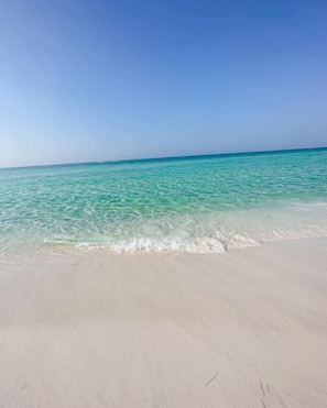Ein Strand mit klarem türkisblauem Wasser und einem sandigen Ufer.