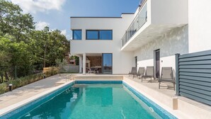 Un bâtiment moderne à deux étages doté d’une piscine, d’un espace extérieur aménagé et offrant une vue sur les environs.