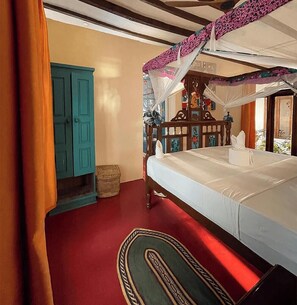 Ein Schlafzimmer mit einem Bett, einem Holz-Kopfteil, einem Nachttisch, einer blauen Tür und einem roten Teppich.