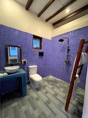 Ein Badezimmer mit blauen Fliesen, einem weißen Waschbecken, einer Toilette und einer Duschkabine.