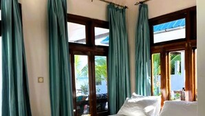 Een bed met witte lakens, een houten hoofdeinde en een vloerkleed met blauwe strepen.