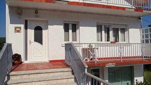 A two-story building with a white facade, a red roof, and a balcony with a metal railing. - Casa Carmelo Spacious house with garden (Serres)
