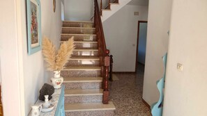 A staircase with a wooden handrail and a vase with dried plants on the landing.