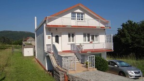 A two-story house with a balcony, a garage, and a car parked in front. - Casa Carmelo Spacious house with garden (Serres)