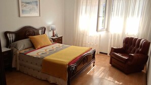 A bedroom with a bed, a nightstand, a chair, and a window with curtains. - Casa Carmelo Spacious house with garden (Serres)