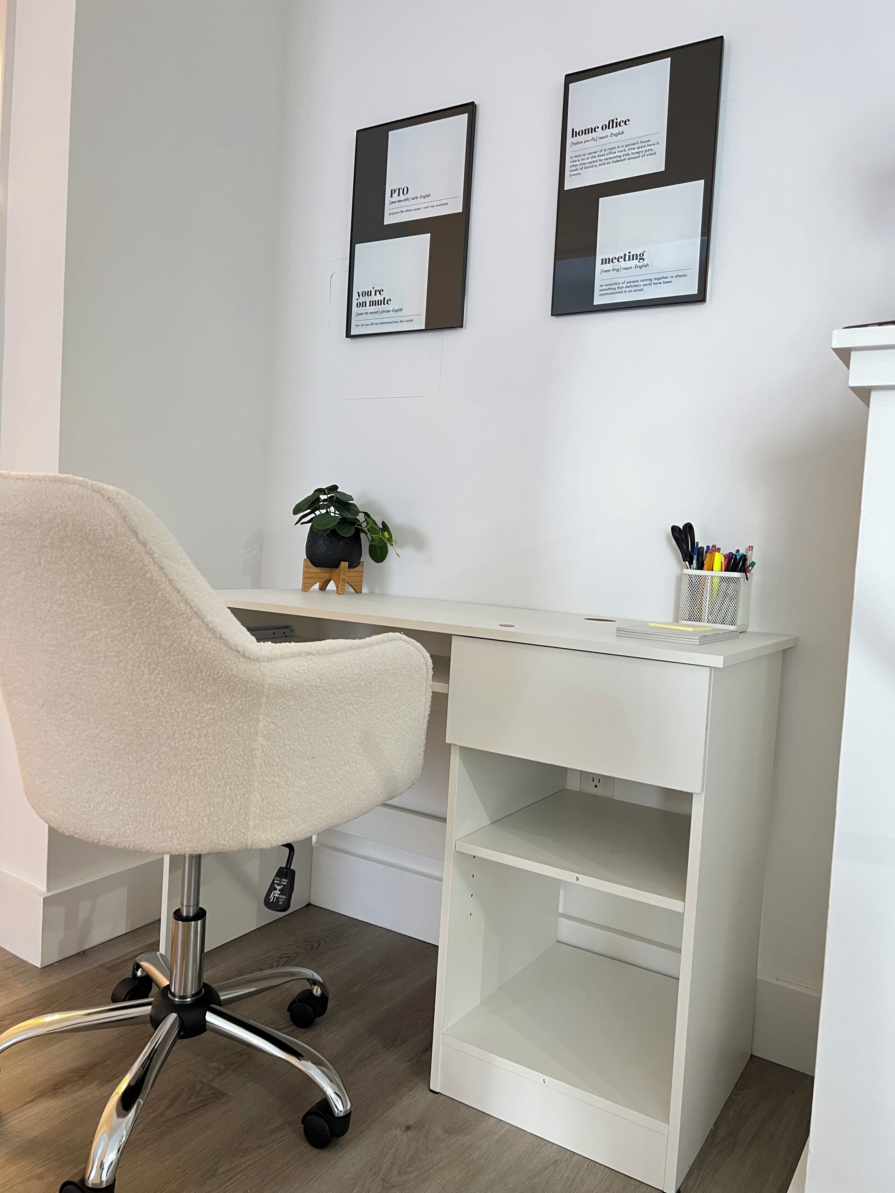 Ein weißer Bürostuhl, ein Schreibtisch, ein Blumentopf und ein an der Wand befestigtes Regal mit Stiften.