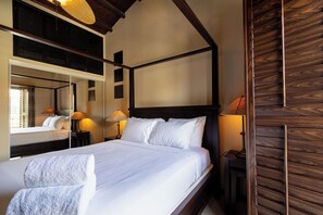 Ein Hotelzimmer mit einem großen Bett, einem hölzernen Kopfteil, einem Spiegel und zwei Nachttischlampen.