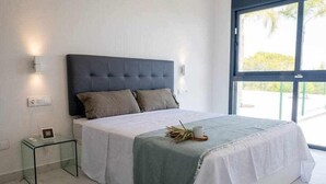 Un dormitorio moderno con una cama grande, una mesita de vidrio y vistas al exterior.