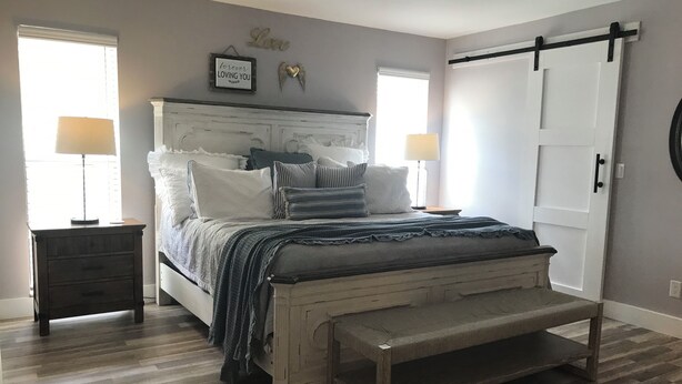 Une chambre à coucher comprenant un lit, des tables de chevet, un banc et une armoire.