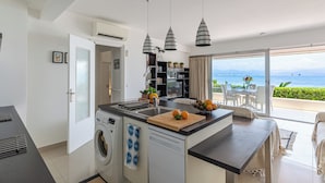 Eine moderne Küche mit Waschmaschine, ein Essbereich mit Tisch und Stühlen sowie Meerblick.
