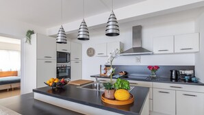 Eine moderne Küche mit Kochinsel, Edelstahlgeräten und Pendelleuchten.