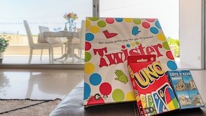 Brettspiele, genannt 'Twister' und 'UNO', auf einem Tisch mit Blick auf eine Terrassenanlage.