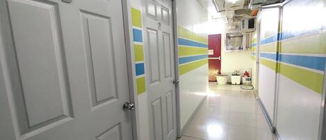 A hallway with white doors, numbered 3 and 2, leading to a room with a red door.