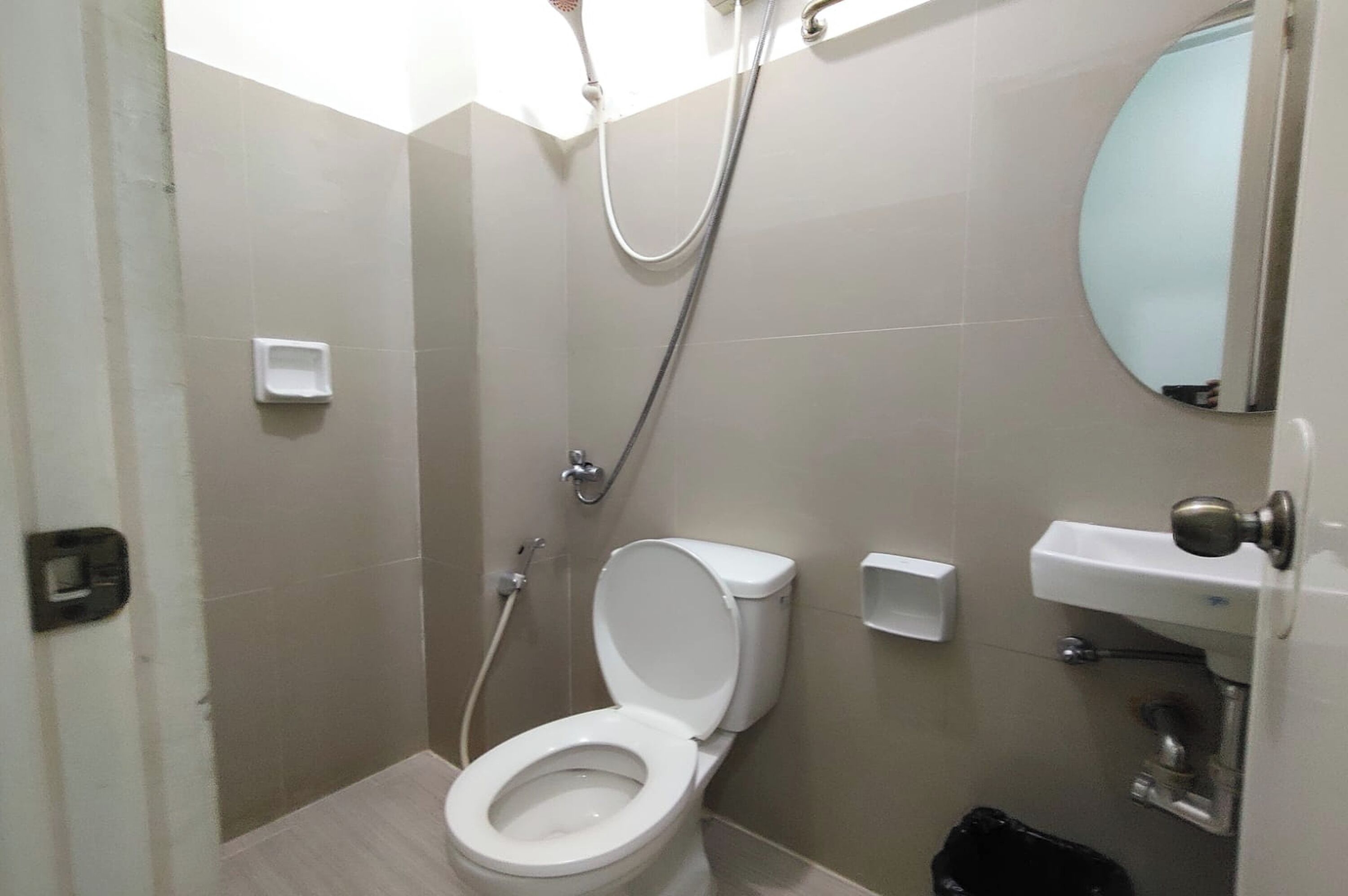 Un baño con inodoro, ducha, lavamanos y espejo.