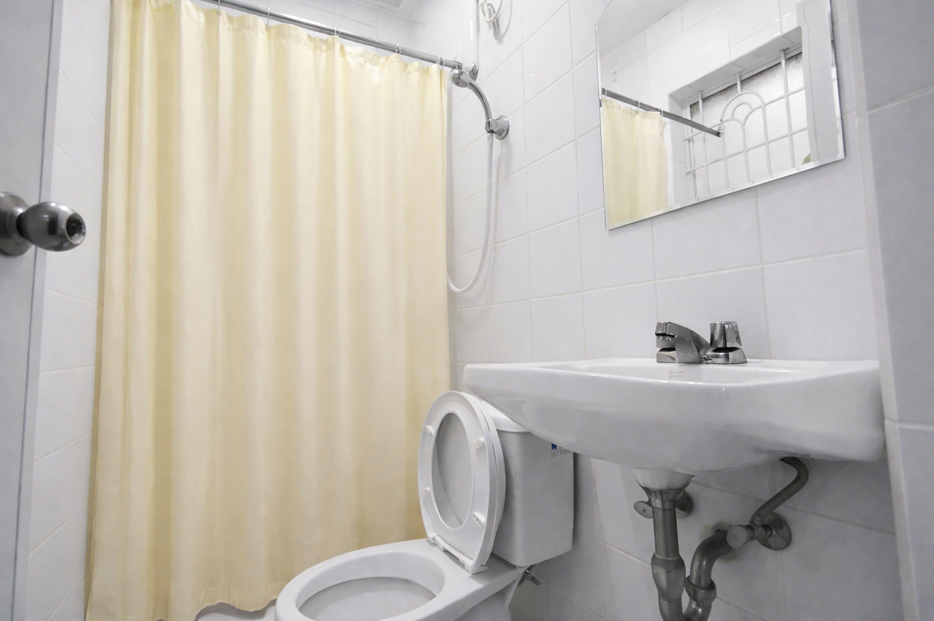 Kylpyhuone, jossa on wc, pesuallas, suihku ja peili.
